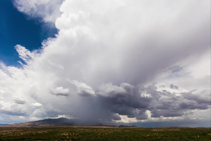A tornado funnel moves under heavy clouds over an open field