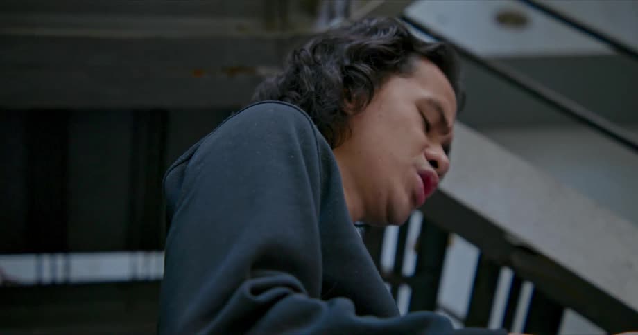 A young man holds a script in front of himself and rehearses it in a stairwell