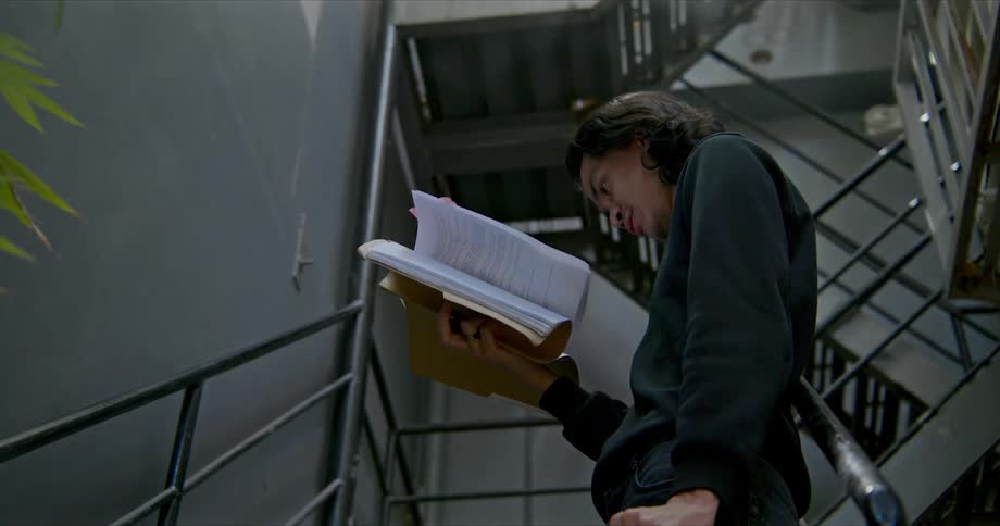A male reading on asteamy stairwell and raising his hand