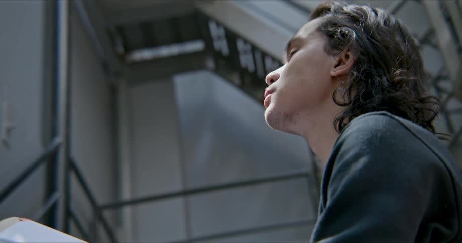 A teenager is distracted and looks up while studying in the stairwell of a multi floor building