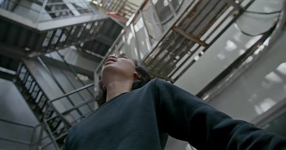 A man holding papers and yelling in a staircase