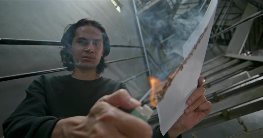 A man lighting paper on fire in anger