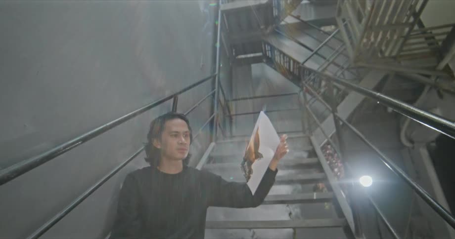 A man burning paper sitting in a staircase