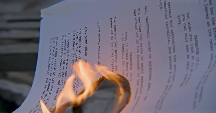 Flames spread further in the center of a stack of papers as the papers fall through the ground