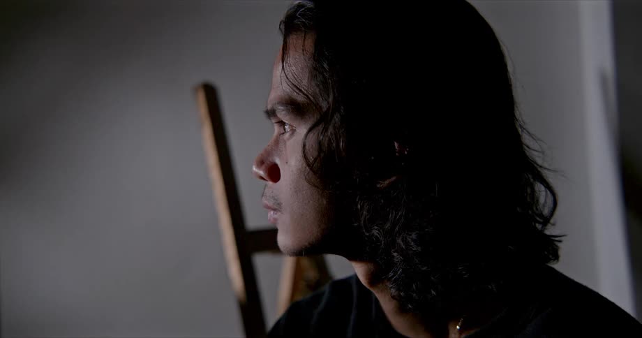 A teenage boy indoors looks towards a bright light