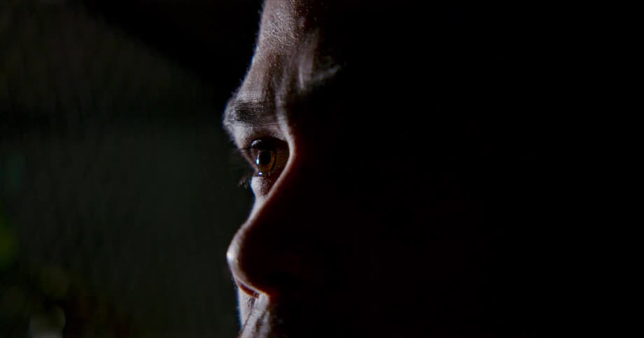 Man stares and blinks his face partly in shadow