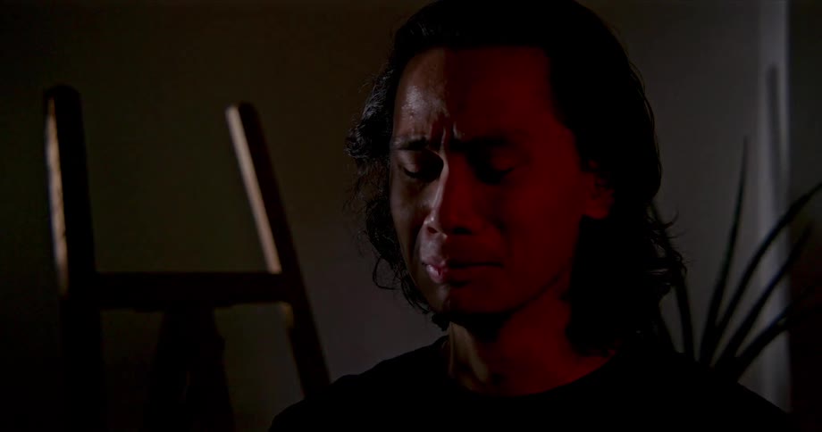 A man indoors cries and looks towards the ground
