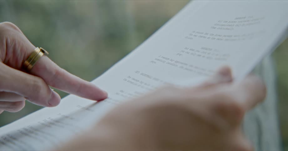A person points at printed text on a page and gestures with their hand