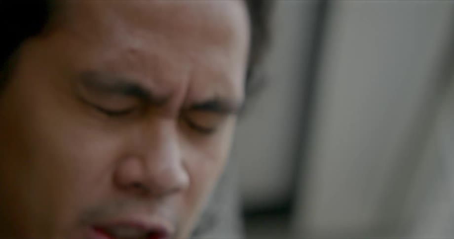 A man indoors closes his eyes and talks