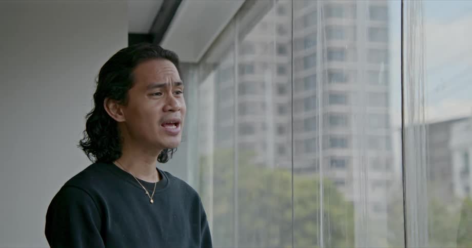 A young man in an office building looks at a paper and sings