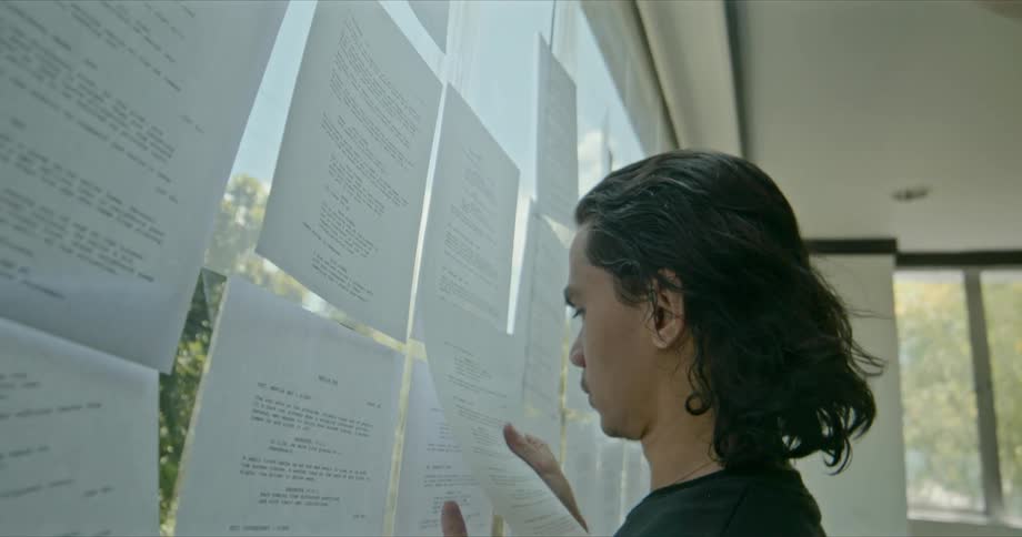 A teenager grabs a piece of paper thats among dozens taped to a large window in a building