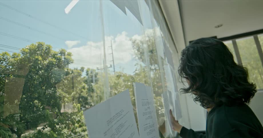 A man angrily rips pages of script off a window where they had been taped up