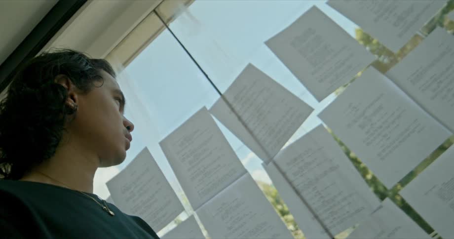 Man stands looking at rows of papers posted on sliding glass doors