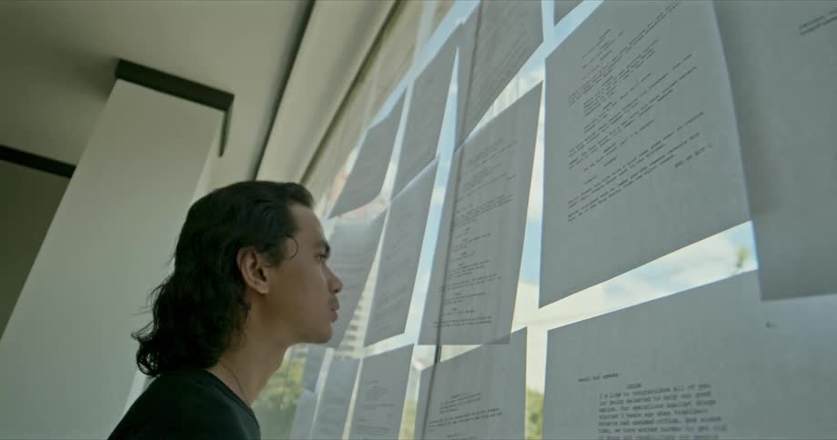 A teenager reads papers taped on a classroom window