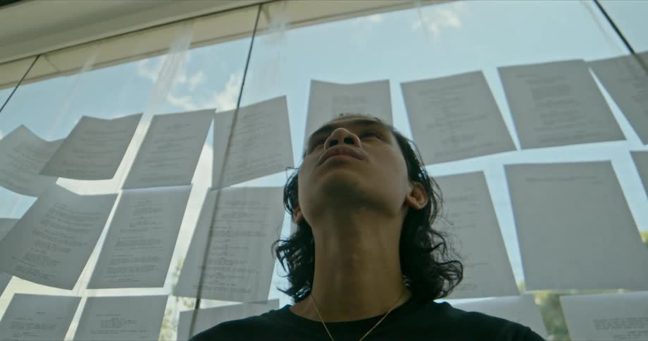 A man sitting in front of a window with paper on it