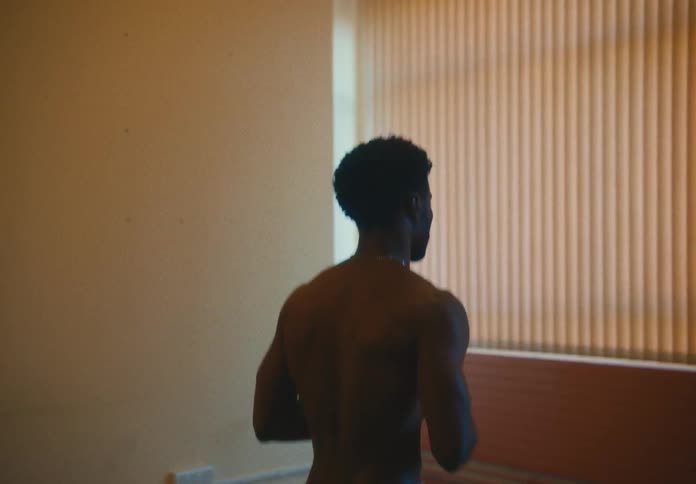 A man jogs in place while indoors then stops and quickly looks over at a window