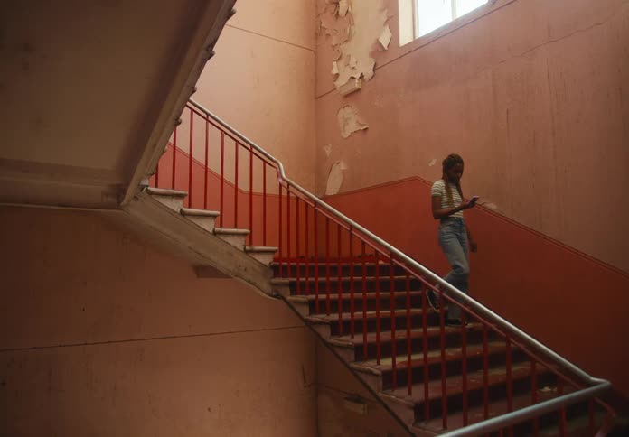 A woman walking down a staircase texting on her phone