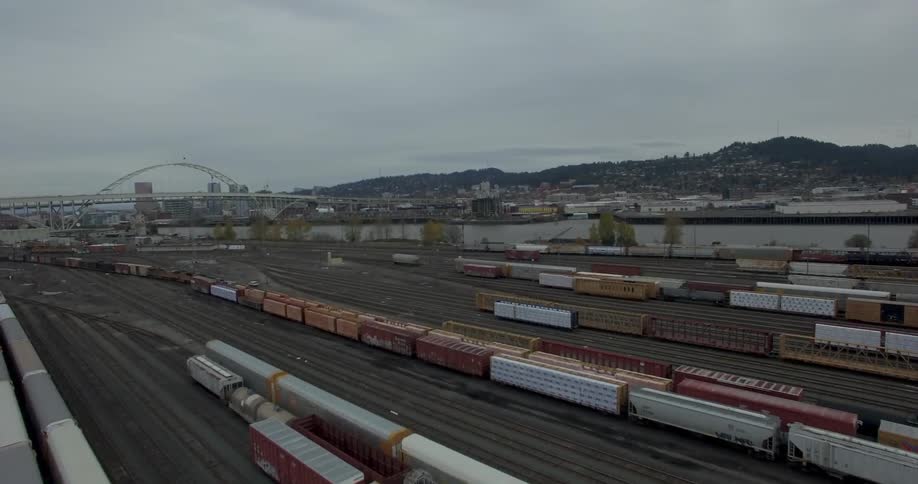 A rail yard under cloudy skies with an arch in the distance
