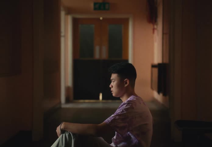 A man sitting on the floor of a hallway with a wall and door in the background