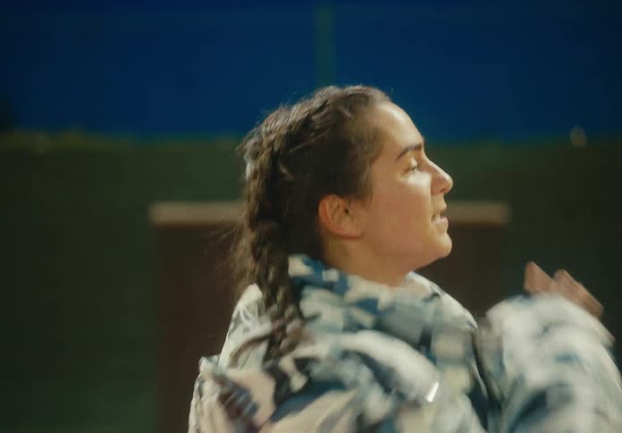 A woman in a puffy coat performs a choreographed dance routine
