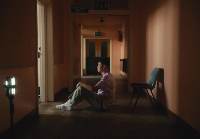 Man sitting on floor in hallway gets up and leaves through open doorway