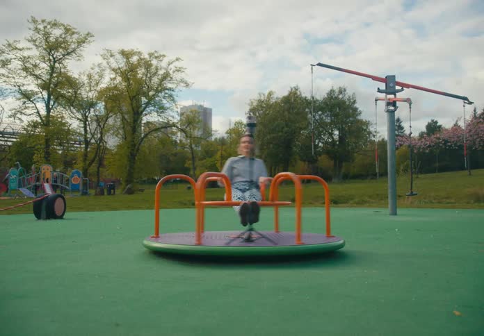 A young female sits on a merry go round with her smart phone capturing images of her spinning