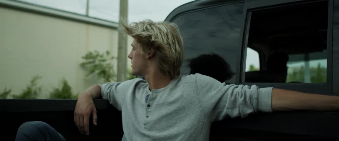 A man looks around as he rides in the back of the pickup
