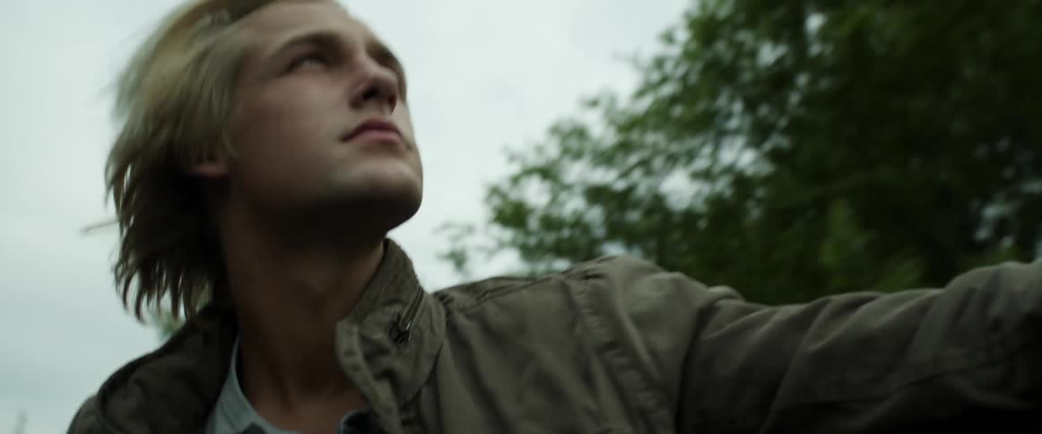A young male relaxes as he sits in the back of a pickup truck that is moving