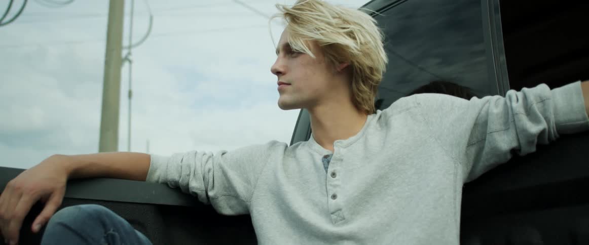 Ayoung man sits in the back of a moving pick up truck