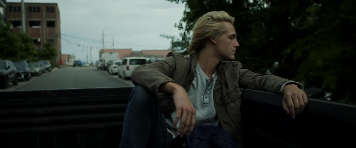 A man riding in the bed of a truck driving down a road