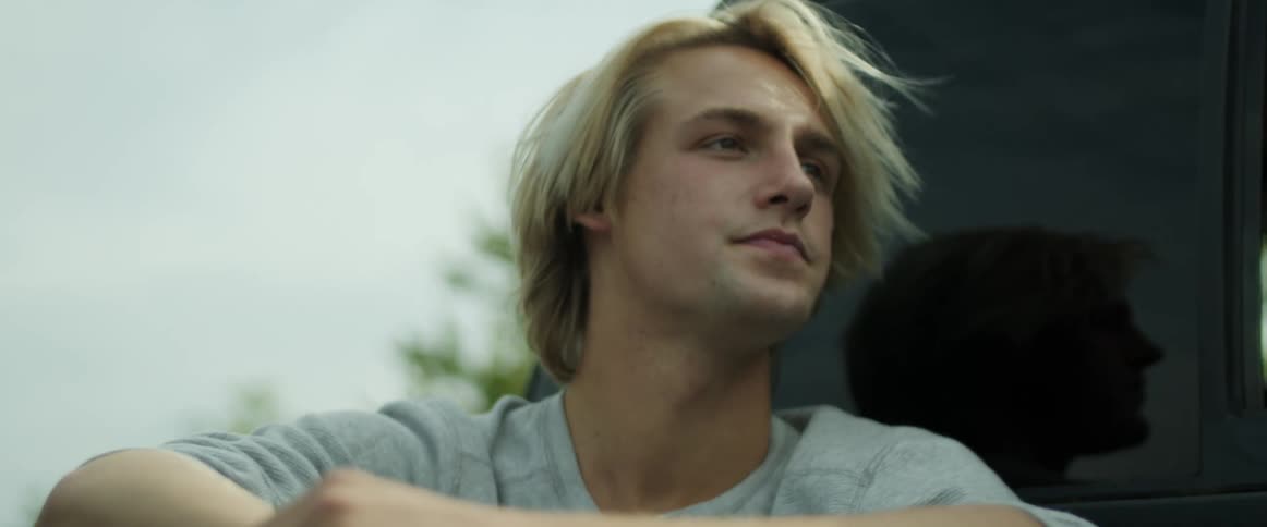 Blonde man rides in truck bed near cab window