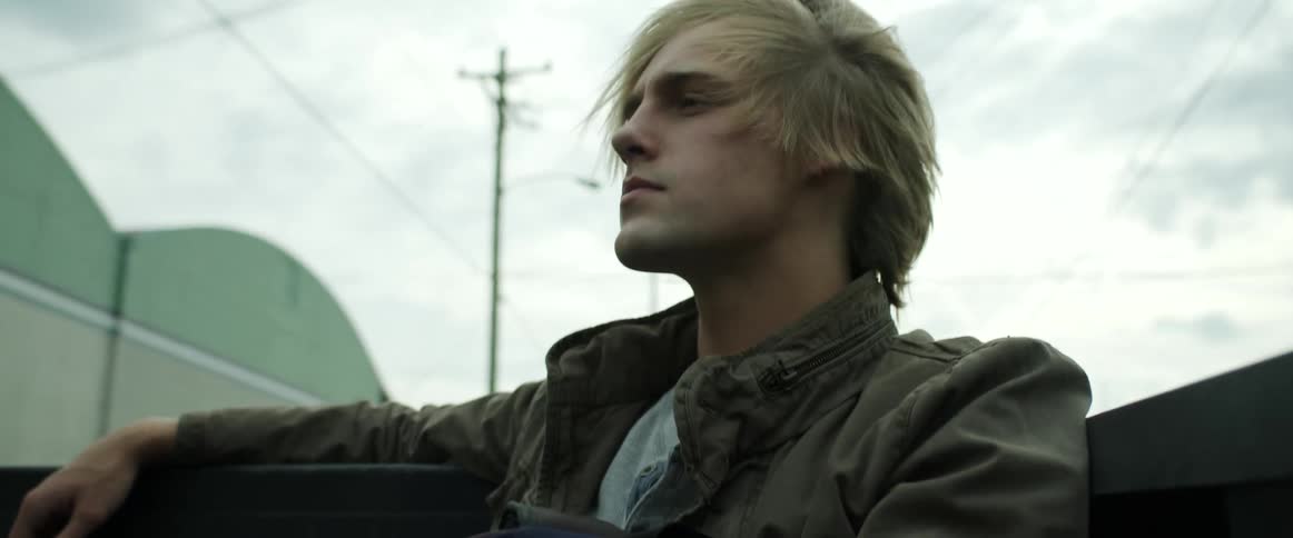 Young blonde man riding the passenger seat in a convertible car