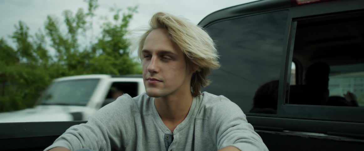 A teenager rides in the back of a moving pick up truck