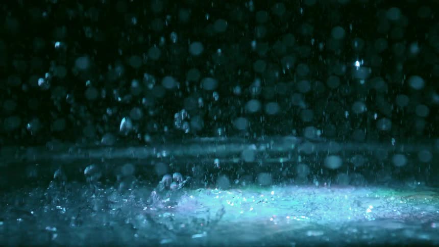 Drops of water splashing to the ground with colorful lights shining from above