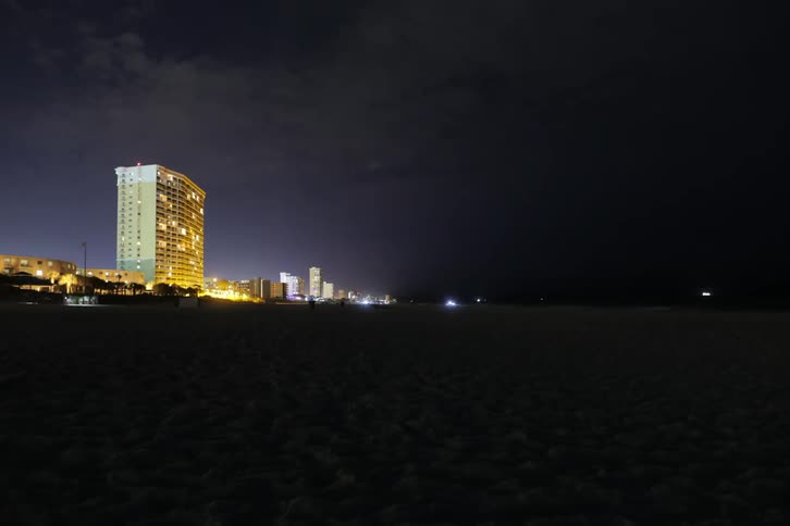 Time lapse of traffic in a dark area with a lighted building shining in the background