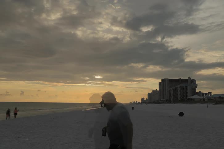Time-lapse of beach activity on a cloudy day and going into the night