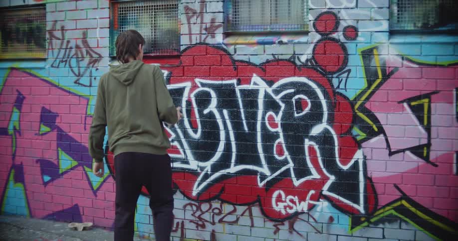 A boy is spray painting on the building