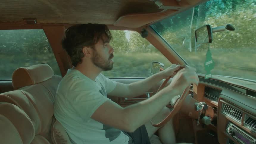 Young man driving a car on a road in the countrisde at daytime