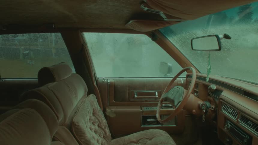 A person holding a mug and washing a car with a hose