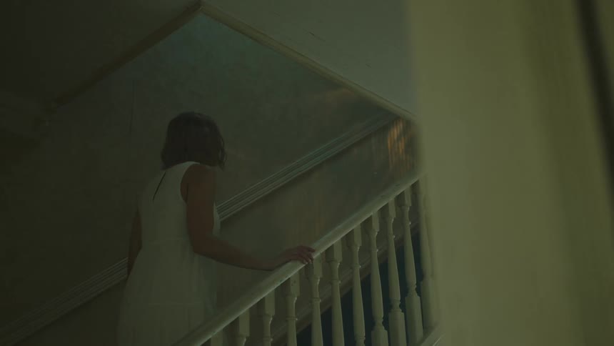 A woman is walking up a flight of stairs indoors