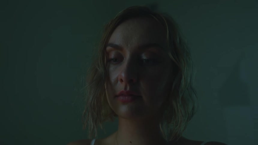 Blonde woman standing in room looks up and around