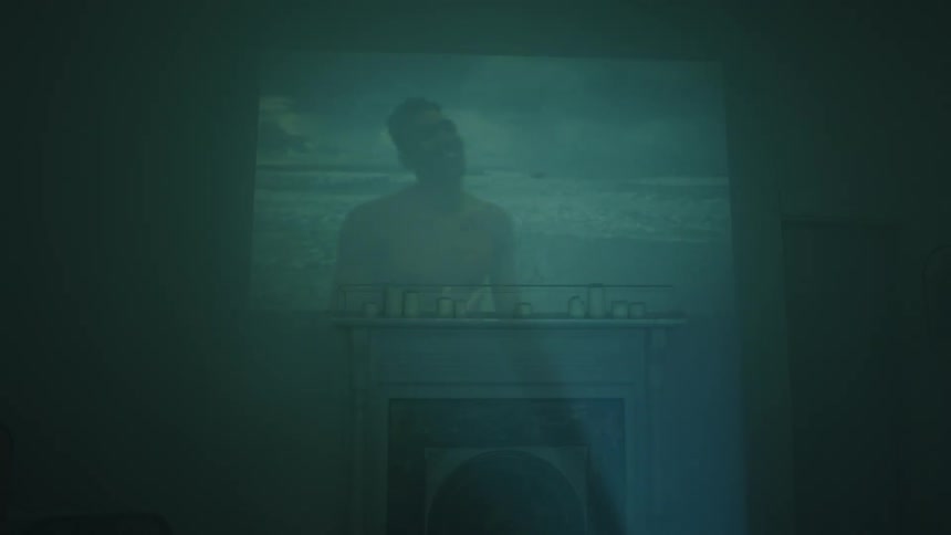 A man laying in bed watching a video on a projector