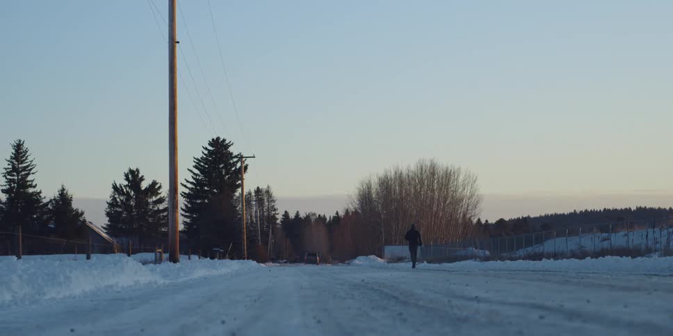 A person runs down a snowy road in a rural area