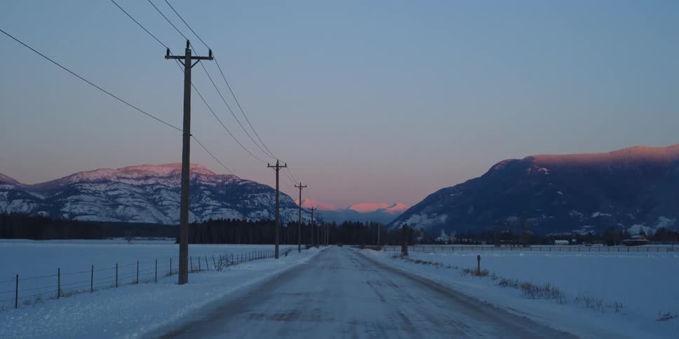 The sun is setting in a rural area in winter
