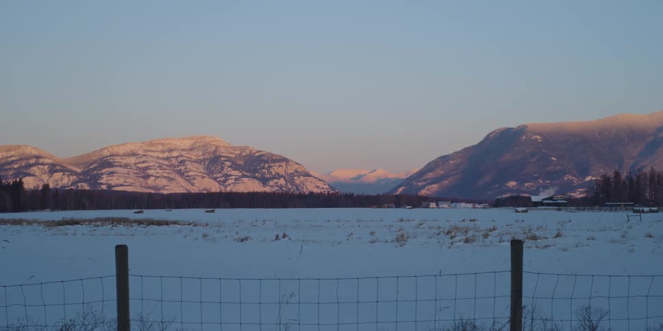 The sun is setting in the horizon above the mountains