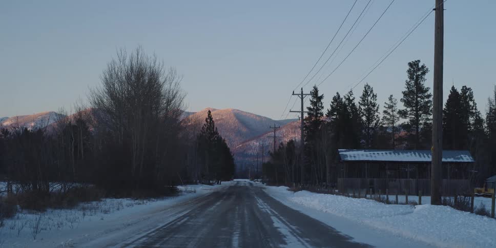 A view of a road in a rural area during winter with snow on the ground