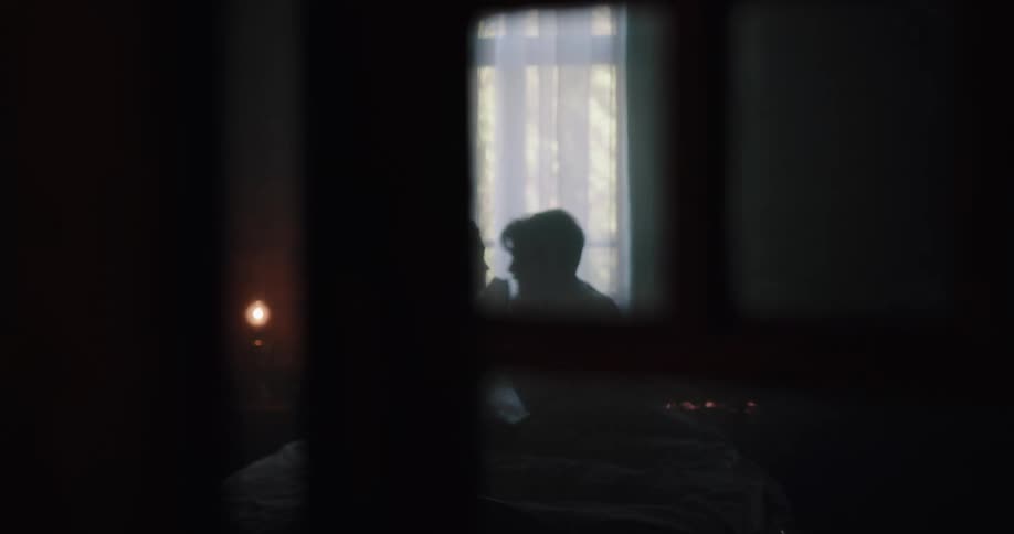 Silhouette of a young couple talking closely while laying in bed in a dark bedroom