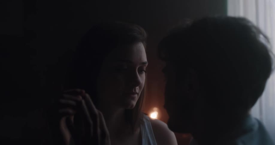 A man and a woman in a room touching each others hand with a wall and window in the background