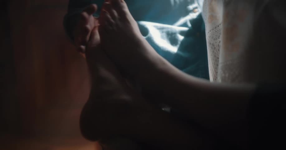 A man walks to a table and sits down as his female companion lifts her foot to have it rubbed