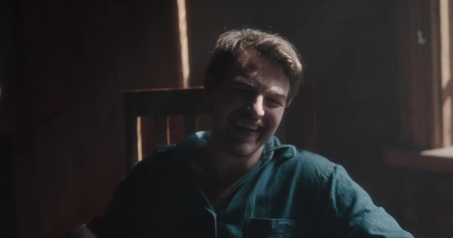 Man sitting in a chair laughs while playing with the barefoot feets of a woman in a cabin